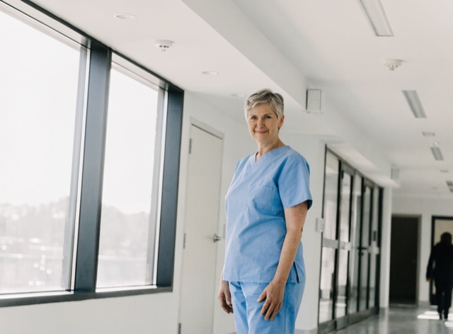 Erfahrene Pflegekraft in einem hellen, modernen Klinikgang